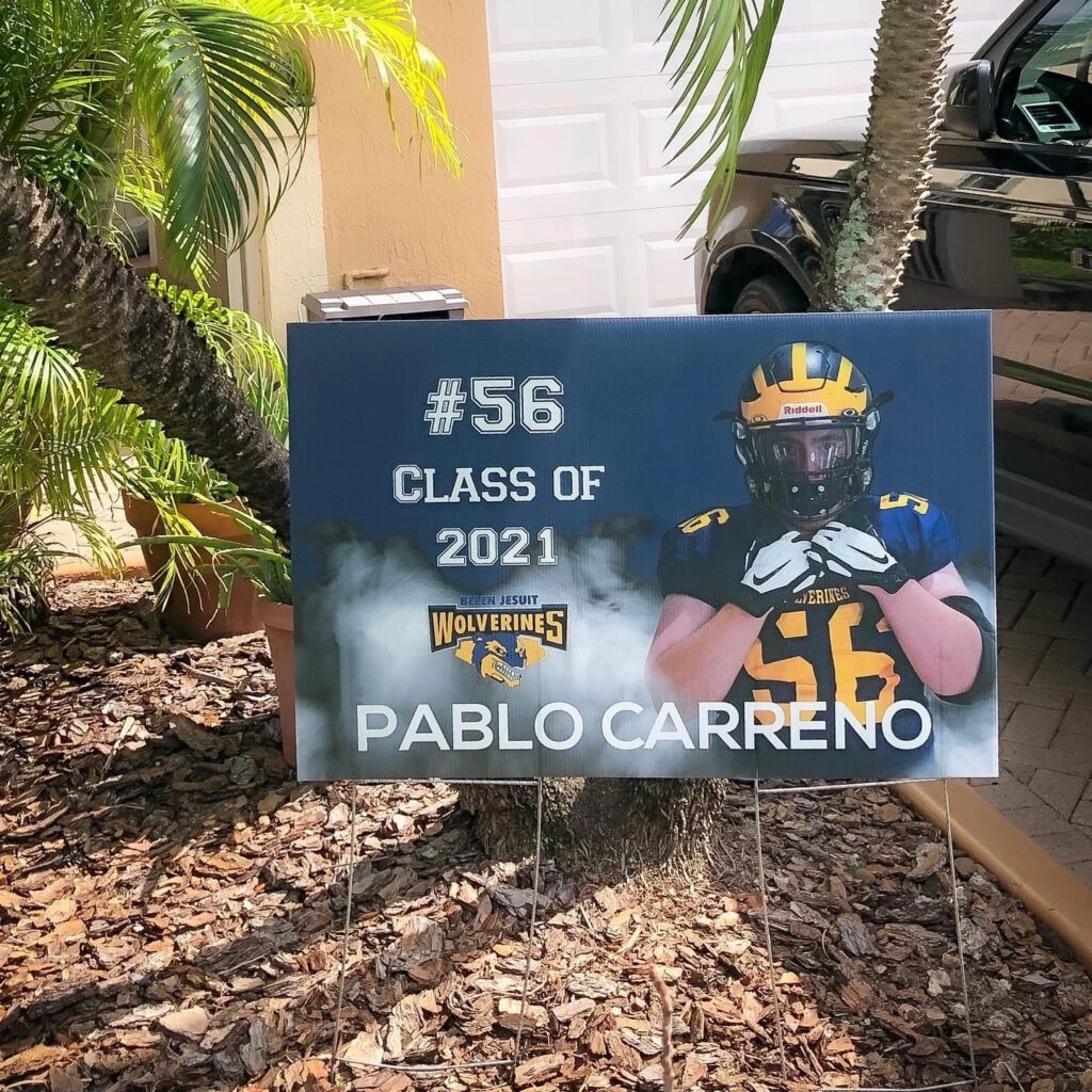 Graduation Yard Sign With Pablo Carreno, Belen Jesuit Wolverines Branding, Number 56 And Class Of 2021 Beside Palm Trees.