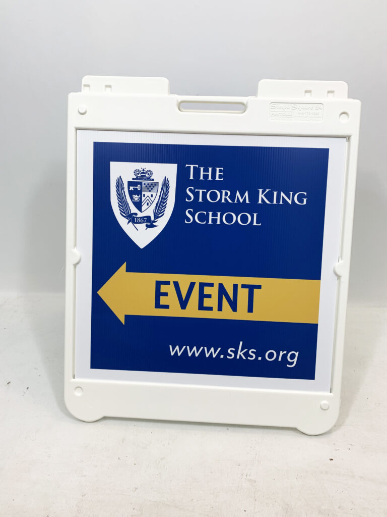 White A-Frame Displaying The Storm King School Crest And A Yellow Left-Pointing Event Arrow On A Navy Panel.