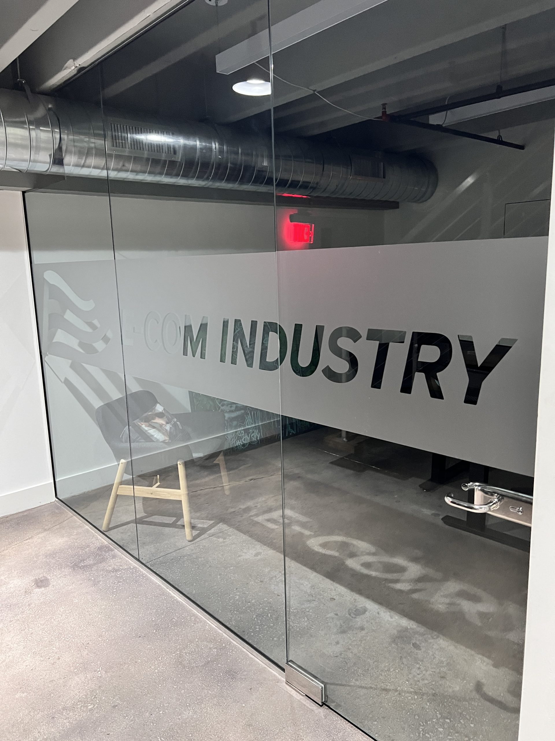 Doral Office Signage And Frosted Glass Graphics | E-Com Industry Glass Door With A Frosted Band, E-Com Industry Lettering, And Logo Graphics In The Office