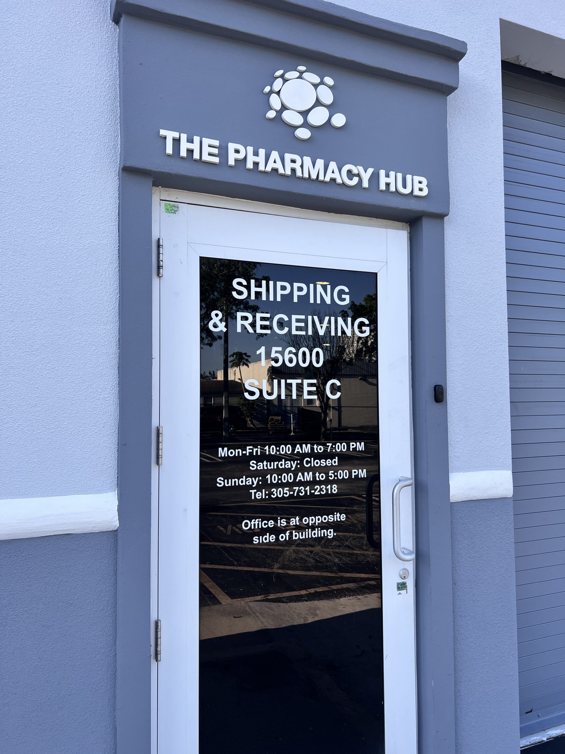 The Pharmacy Hub Pharmacy Signage In Miami Gardens White Vinyl Shipping And Receiving Lettering On A Reflective Glass Entrance Door