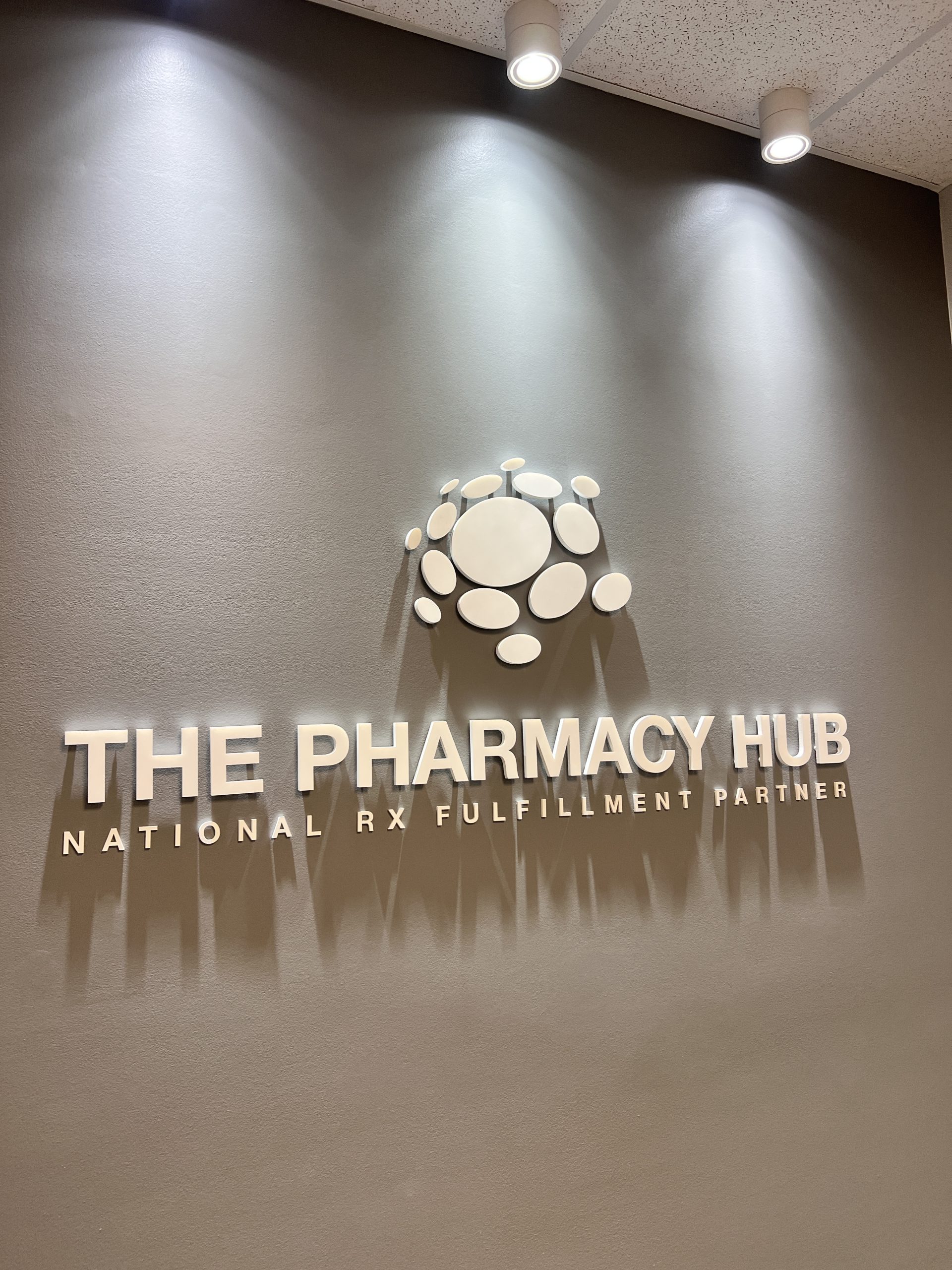 White raised acrylic dimensional logo sign with tagline on a dark gray lobby wall